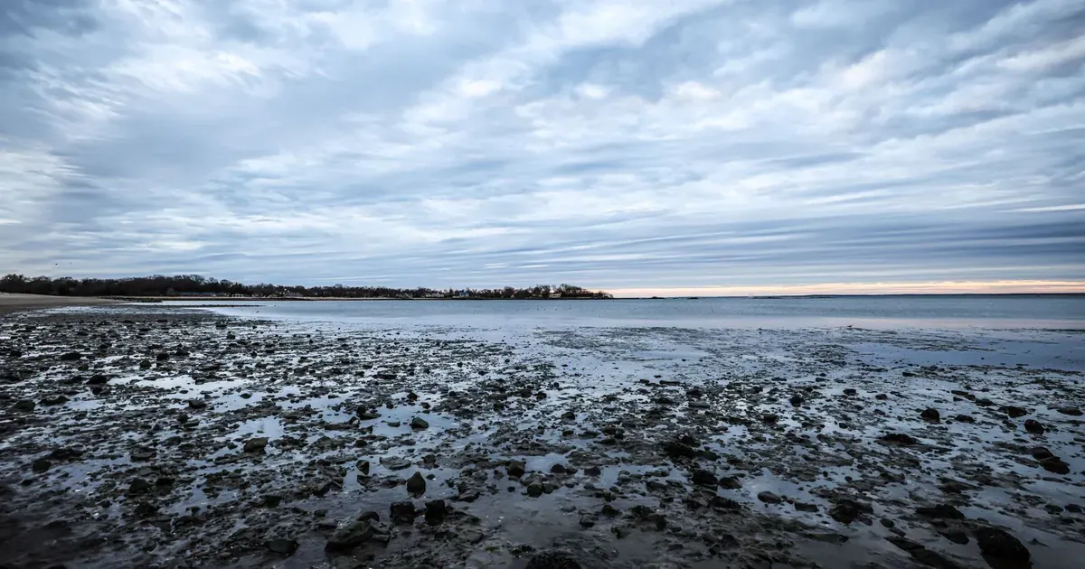 Nuvens baixas sobre uma linha de horizonte, evocando o peso na base do crânio da dor na nuca