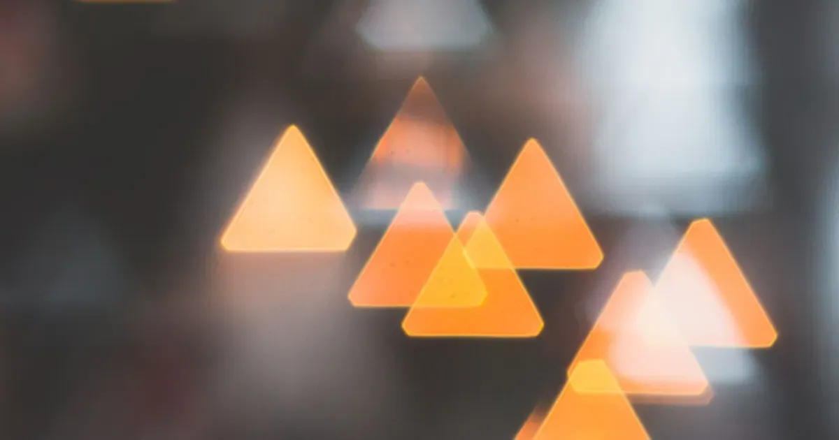 Formas triangulares luminosas e desfocadas em tons de laranja sobre fundo escuro, evocando o escotoma cintilante da aura visual da enxaqueca